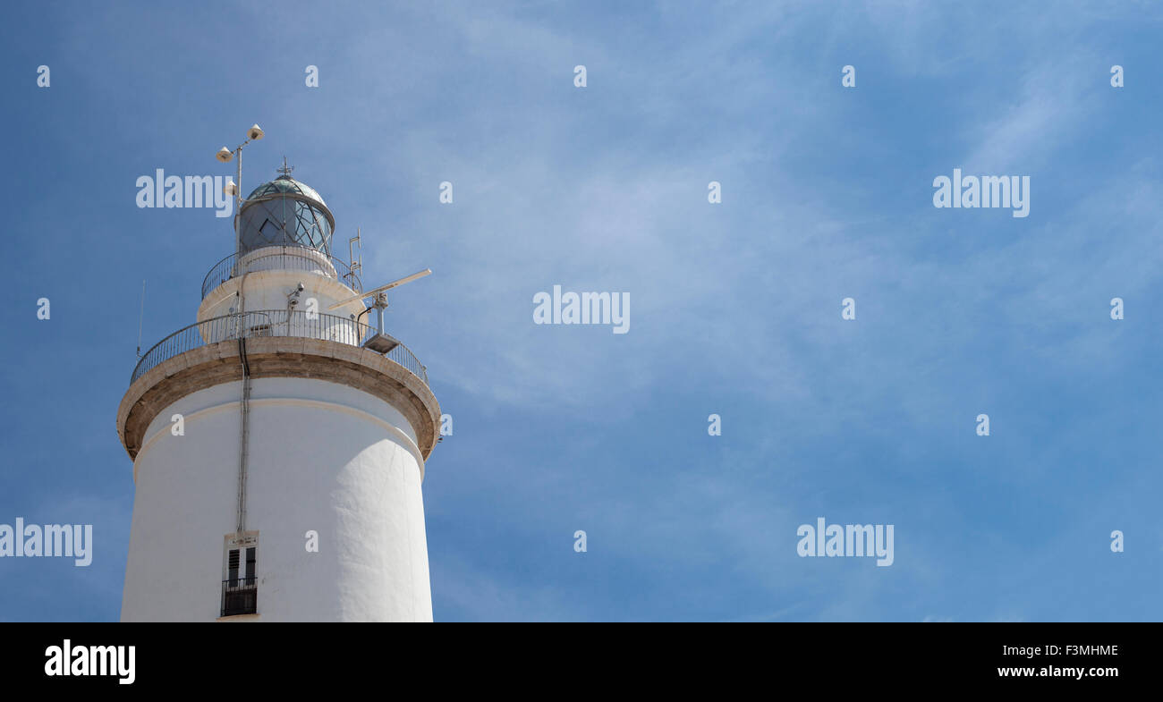 A white whitewashed lighthouse isolated over blue sky with clouds Stock Photo
