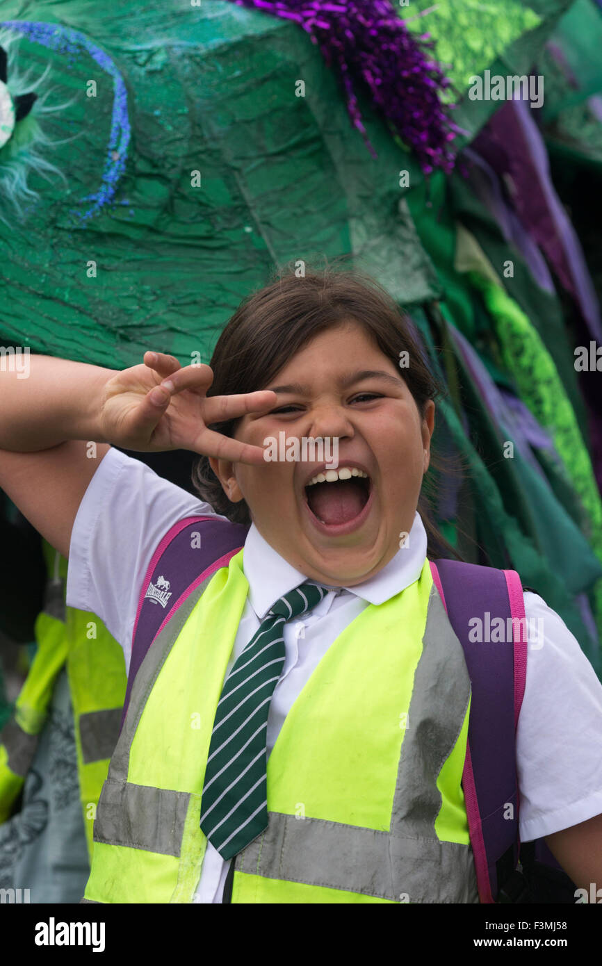Falmouth, UK. Friday the 9th of October 2015.Girl carrying a dragon costume float shows a peace symbol at the Falmouth Oyster Festival Parade 2015 through Arwenack street in Falmouth. Credit:  Michael Hirst/Alamy Live News Stock Photo