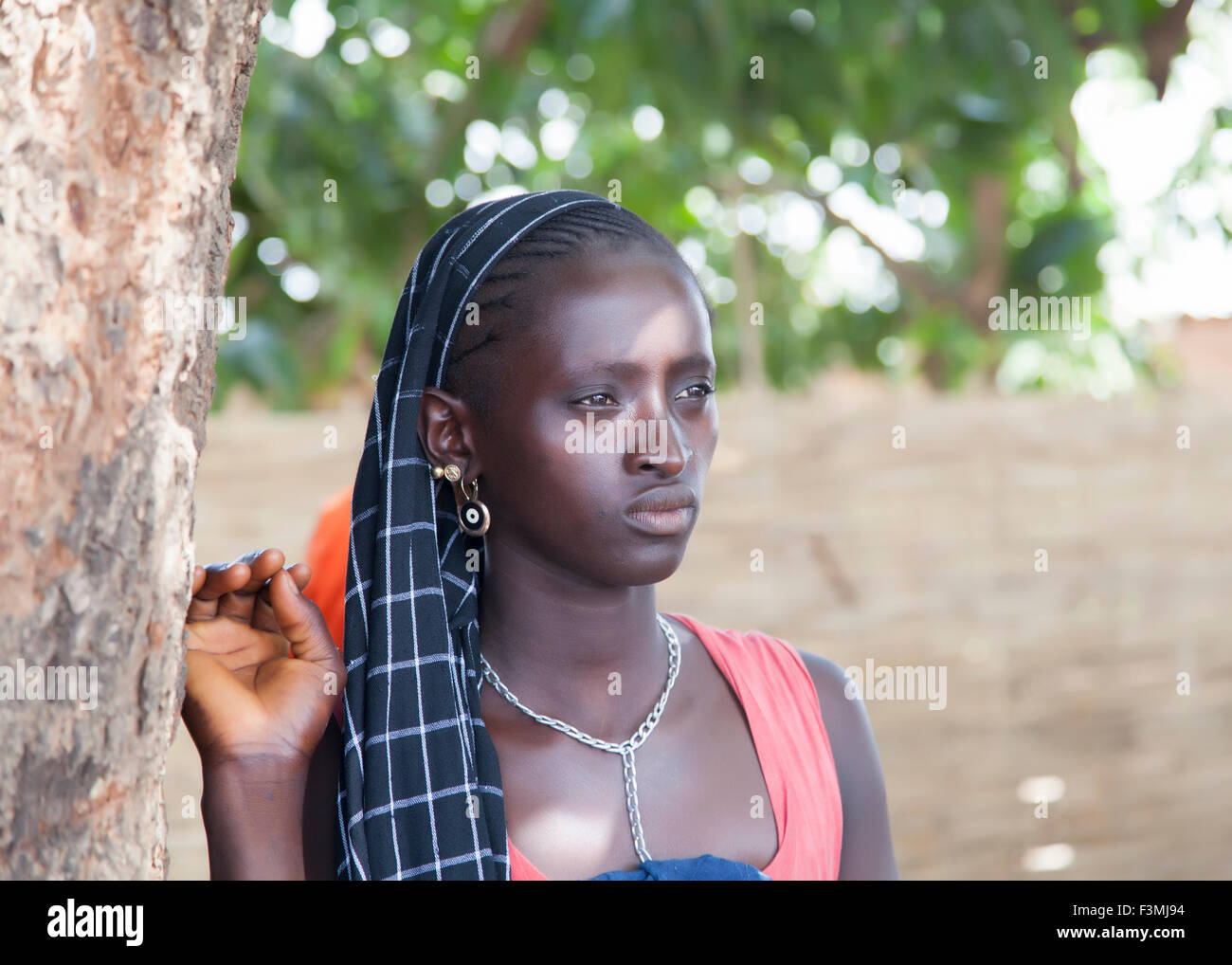 Portrait of an unidentified beautiful African girl paying attention to a speech delivered by the village chief Stock Photo