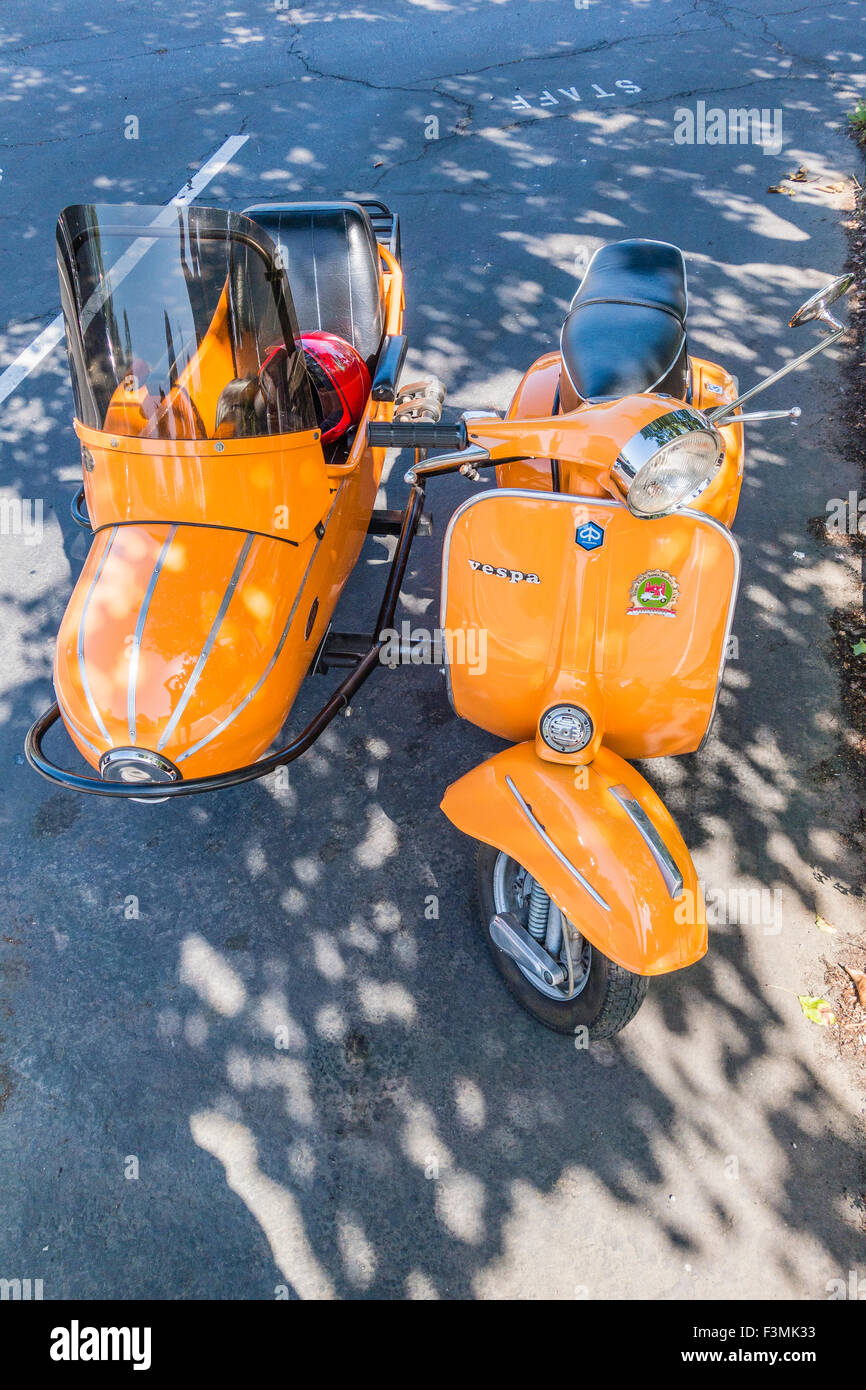 Orange Vespa motorscooter with sidecar parked in shade in Santa Barbara, California. Stock Photo