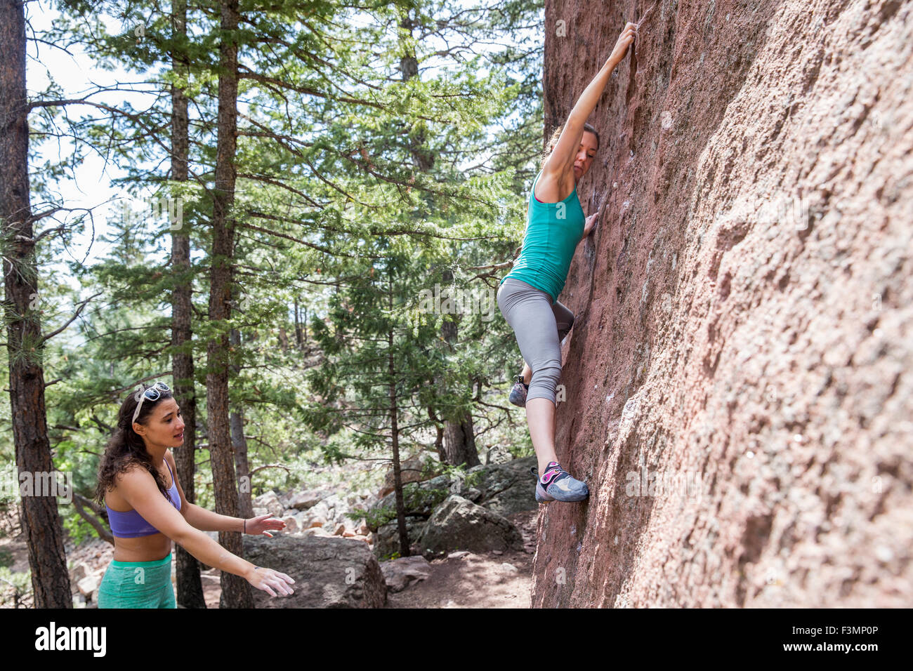 Athletic female traverses as climbing partner assists from below Stock Photo
