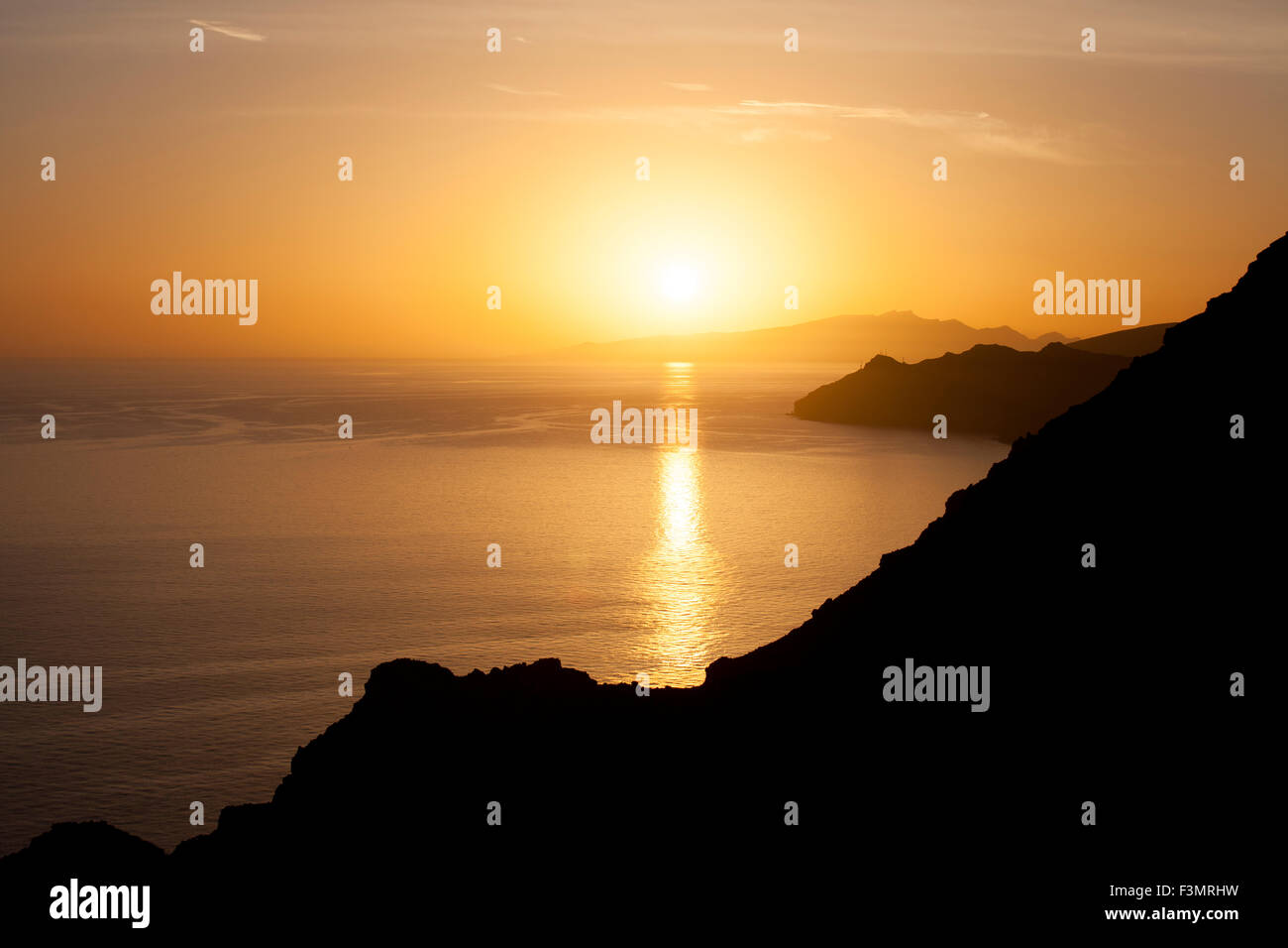 Golden sunset on the ocean with some cliff silhouette Stock Photo - Alamy