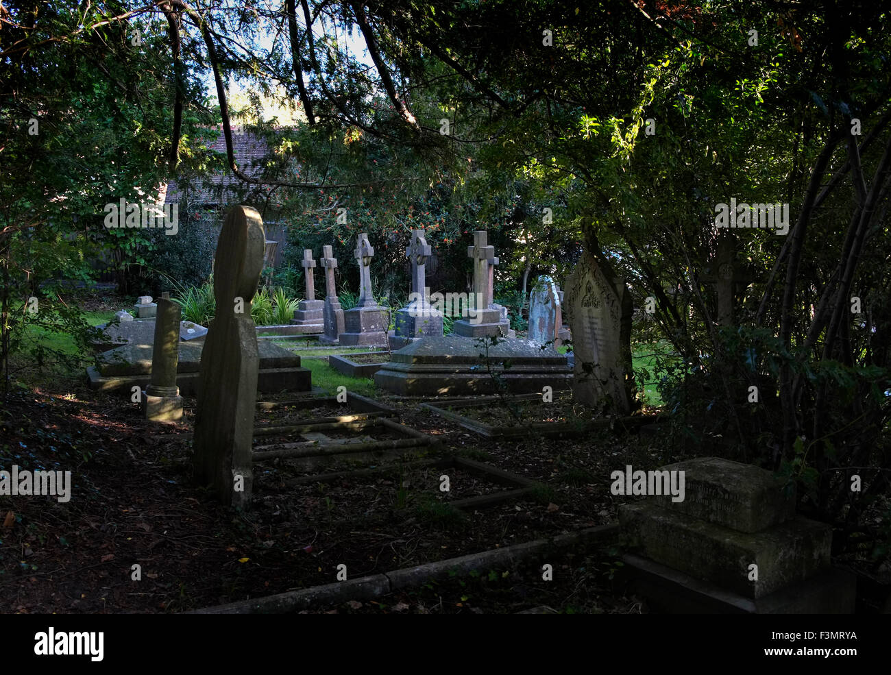 Graves in the graveyard of a Victorian church in Sneyd Park, Bristol surrounded by Yew trees, a UK Stock Photo