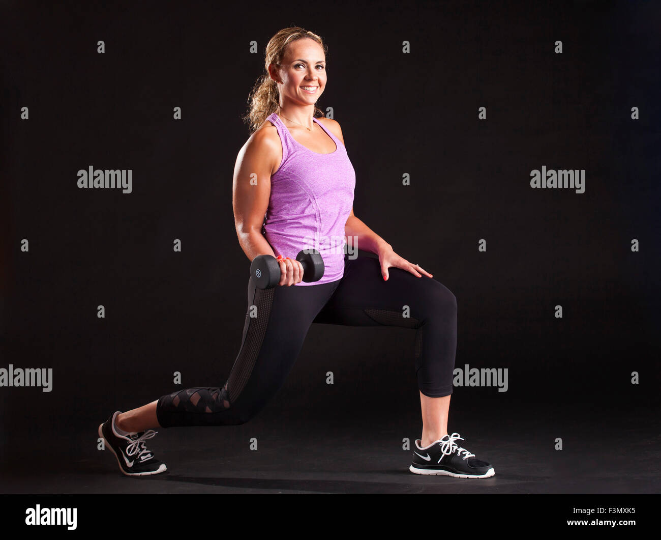 Woman lunging and lifting weight Stock Photo
