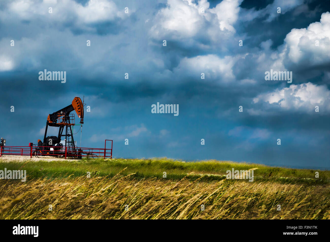 A single oil rig on the windly prairies, with stormy skies. Stock Photo