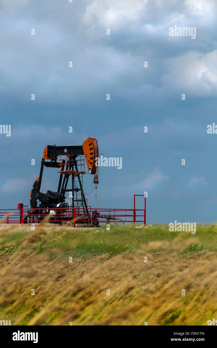 A single oil rig on the windly prairies, with stormy skies. Stock Photo