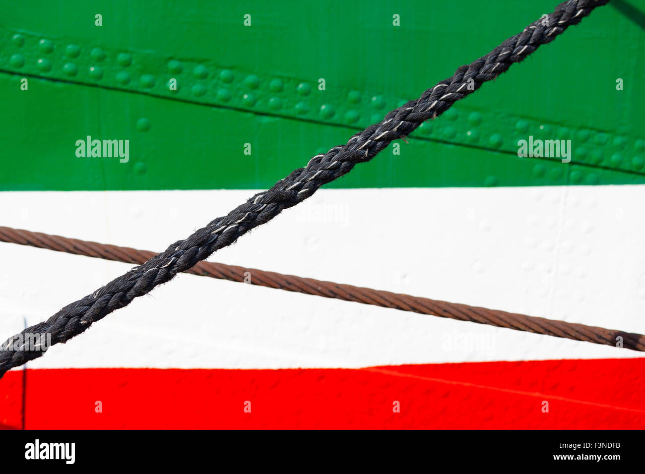 A colorful ship hull in green, white and red with some ropes. Stock Photo