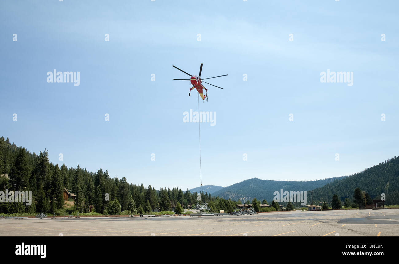 Hovering industrial helicopter in process of lifting construction material.  Dramatic view of the chopper.  Room for graphics. Stock Photo