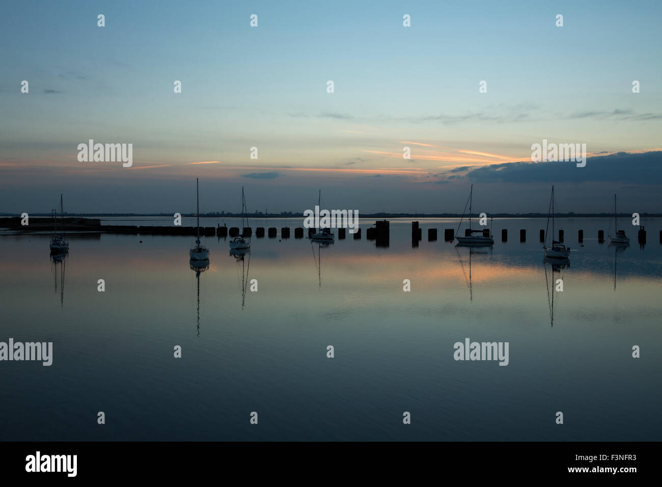 Sunset on the Hayling Billy bridge. View across Langstone harbour towards the setting sun behind Portsmouth on a calm evening. Stock Photo