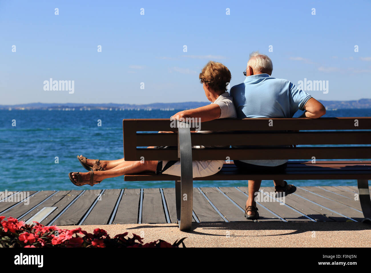 Man and woman resting on a bench, Bardolino, Lake Garda, Italy Stock Photo