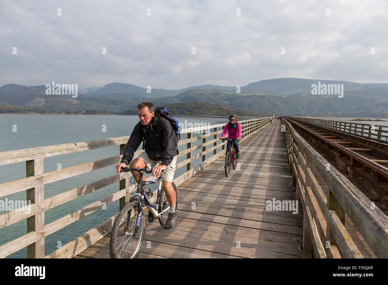 Cyclists on Barmouth Bridge also known as Barmouth Viaduct crossing the Mawddach estuary, Gwynedd, Wales, UK Stock Photo