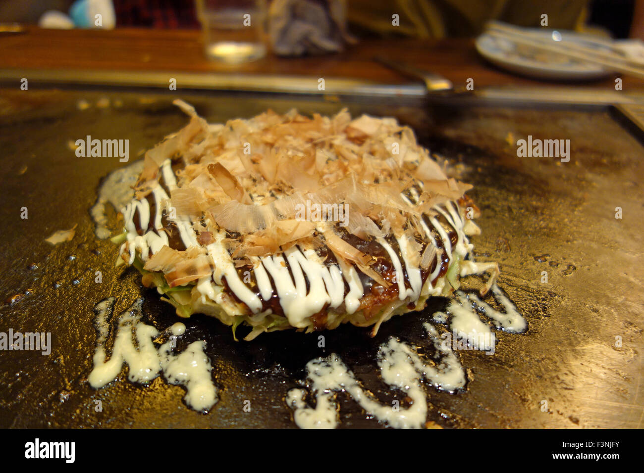 Okonomiyaki on a table-top grill in a restaurant in Osaka, Japan ...