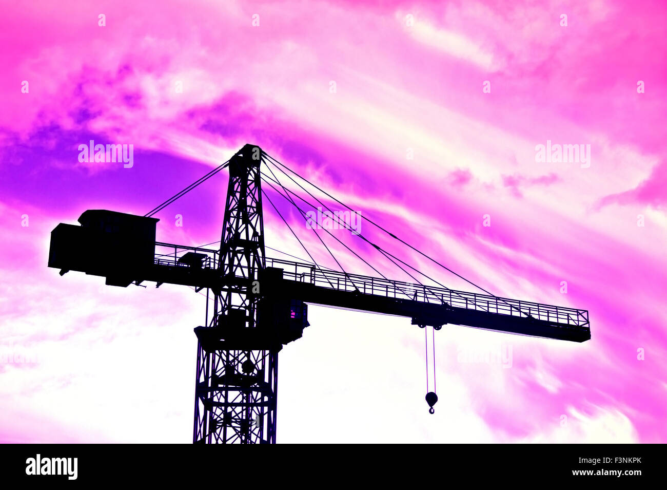 Industrial conceptual image. Purple clouds over industrial area with crane. Stock Photo