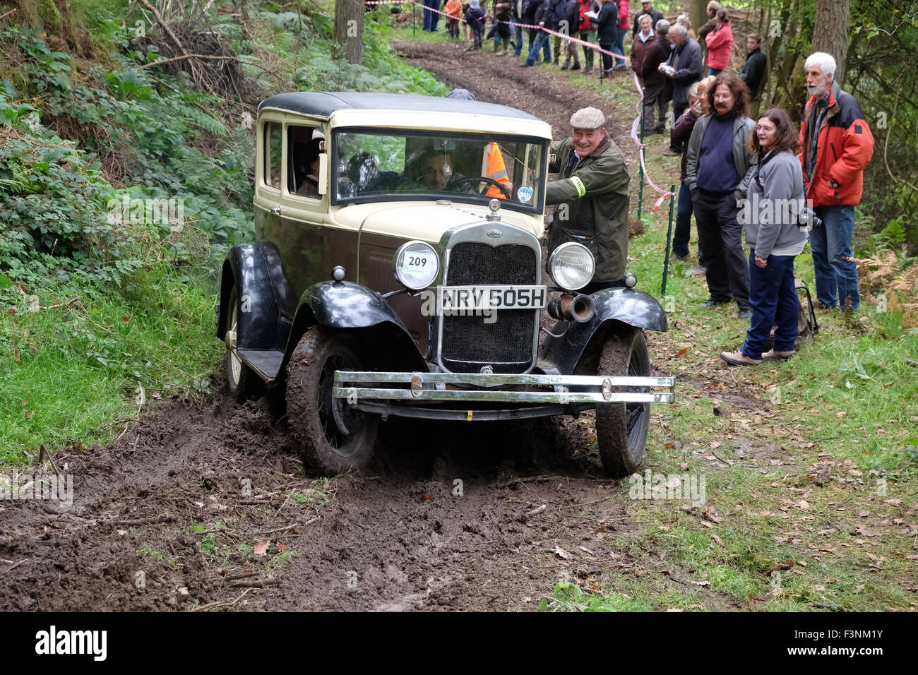 New Radnor, Powys, Wales - Saturday 10th October 2015 - The Vintage Sports Car Club ( VSSC ) hill climb trial challenge on The Smatcher a steep wooded hill just outside New Radnor. This Welsh Trial has been running since 1939. Competitors score points the further they drive up the steep hill with 25 points being awarded for reaching the top. The passenger act as 'bouncer' who bounces to help the car grip on the steep sections. Shown here is a 1930 Ford Model 'A' struggling on the muddy climb. Stock Photo