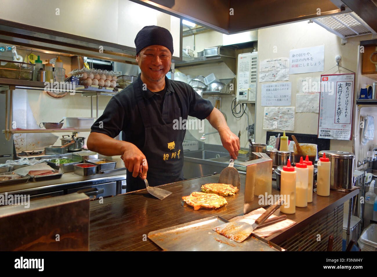 Smiling Japanese chef cooking Okonomiyaki in a restaurant in Osaka, Japan. Stock Photo