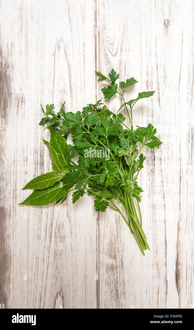 Parsley and bay laurel leaves on wooden background. Fresh organic herbs. Healthy food ingredients Stock Photo