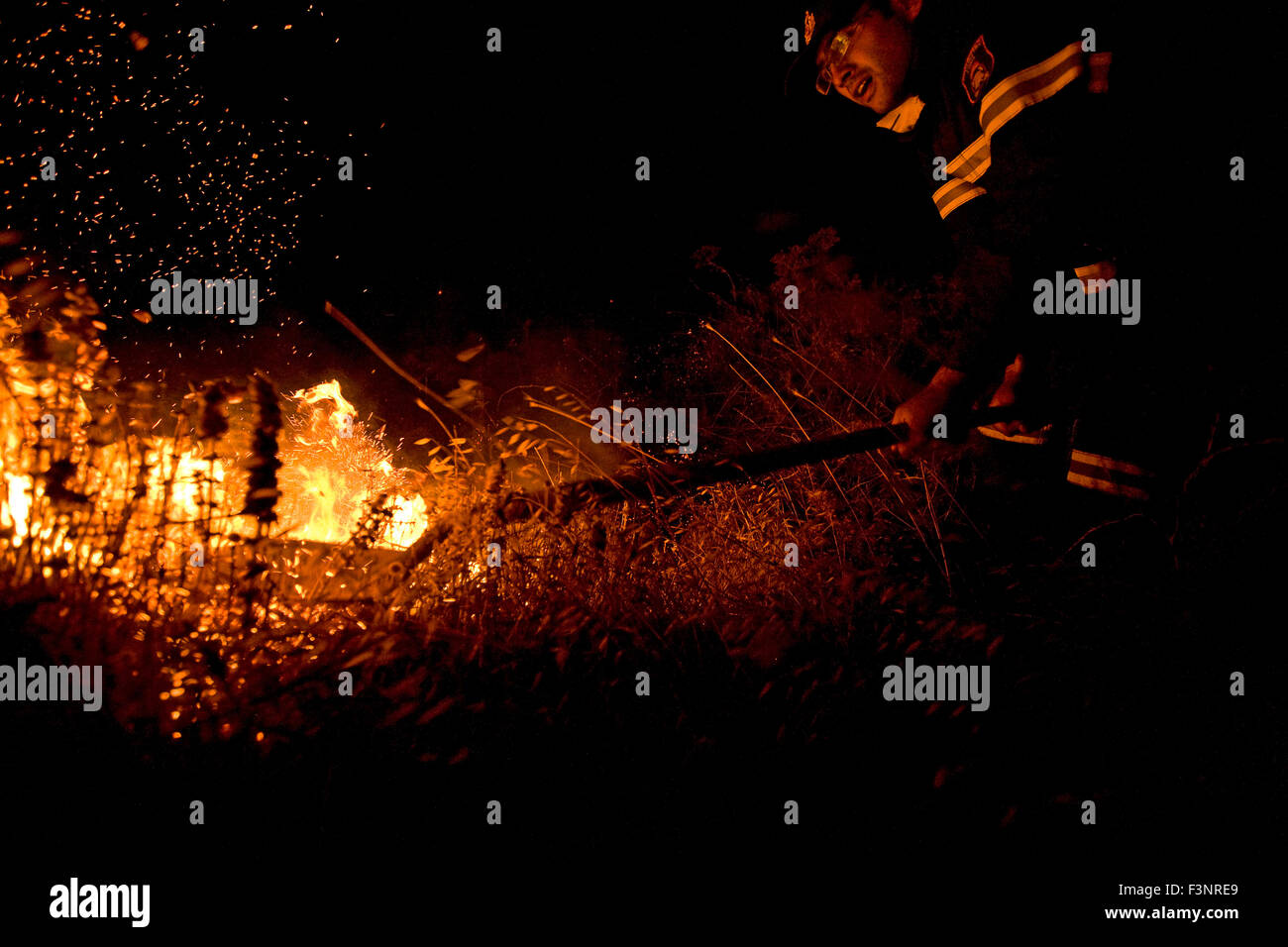 One fireman that arrived on Vorvonas at night, tries to fight fire using a spade causing fire sparks to fly in the air. Stock Photo