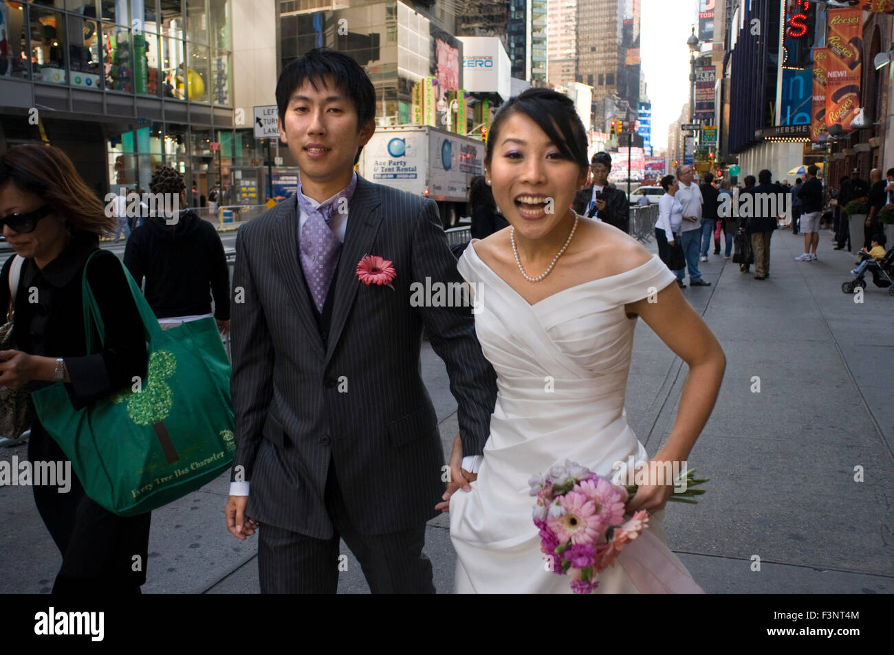 A newly married Asian couple celebrating their honeymoon in the area of Times Square. In the center of this spectacular combinat Stock Photo