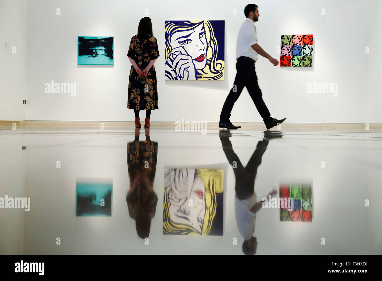Christie's employees pose with artist Roy Lichtenstein's artwork ' Crying Girl' (C), Andy Warhol's 'Little Electric Chair' (L) and 'Self Portrait' at Christie's Auction House in London, UK Friday October 9, 2015.  .  They are all expected to achieve US $9million dollars when they come to auction in New York in November.  They will be on dispay in the UK during Frieze Art Fair week until October 17. Stock Photo