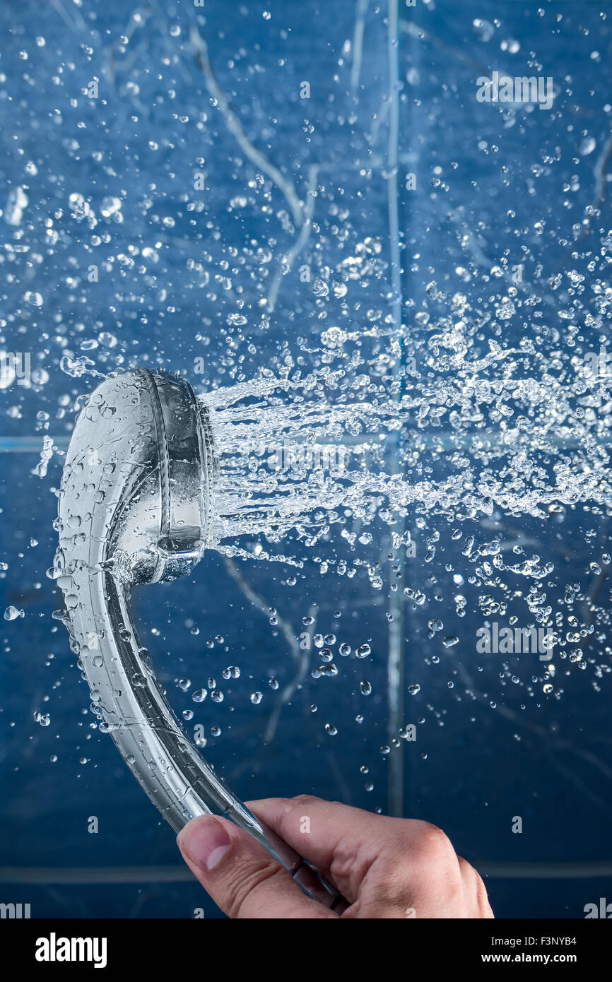 Hand with a shower head is spraying water. Flowing water from the ...