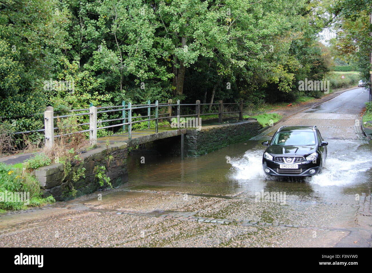 A car drives through a ford on the A614 by Rufford Abbey Country Park in Nottinghamshire, England UK Stock Photo