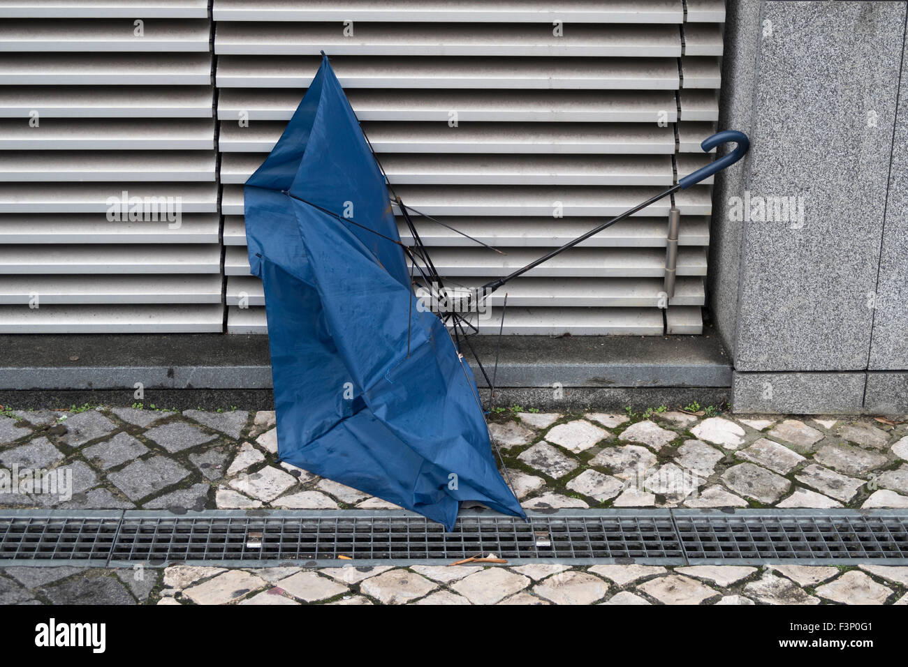 Broken umbrella tossed on the street resulting from bad weather Stock Photo