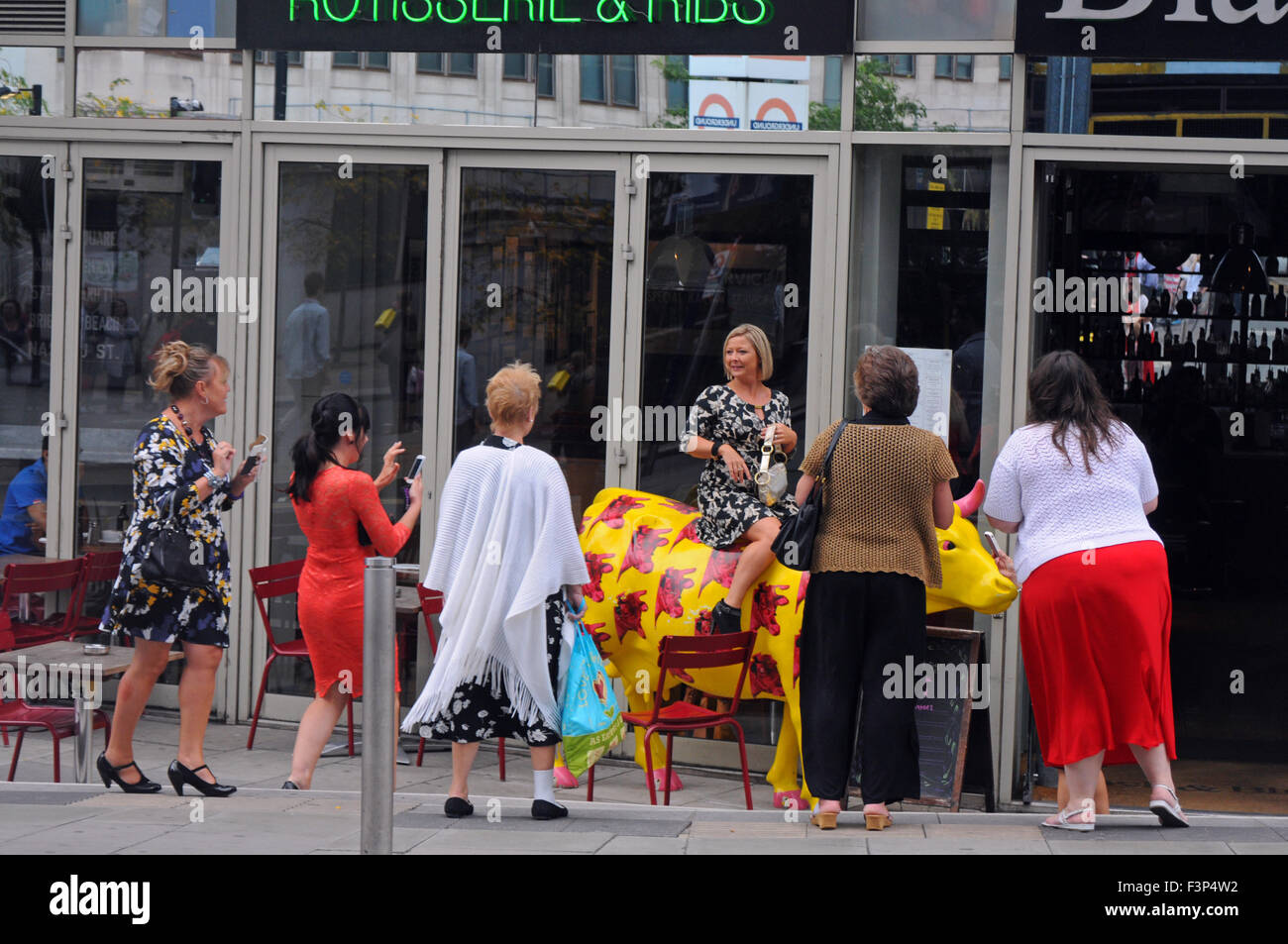 London, UK, 21 September 2014, Girls day out, high spirited one climbs on cow at restaurant on their way to Waterloo station. Stock Photo
