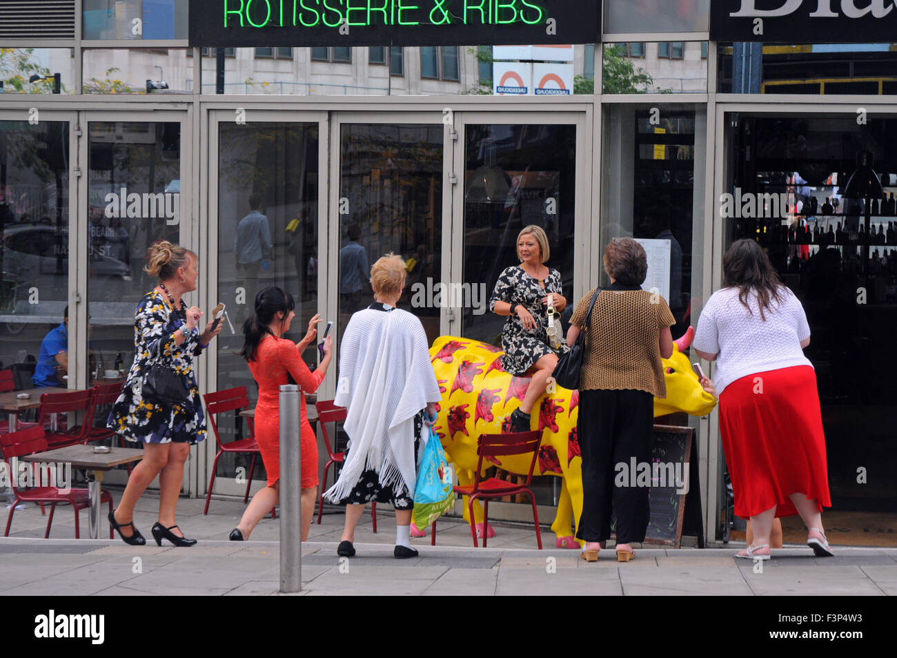 London, UK, 21 September 2014, Girls day out, high spirited one climbs on cow at restaurant on their way to Waterloo station. Stock Photo