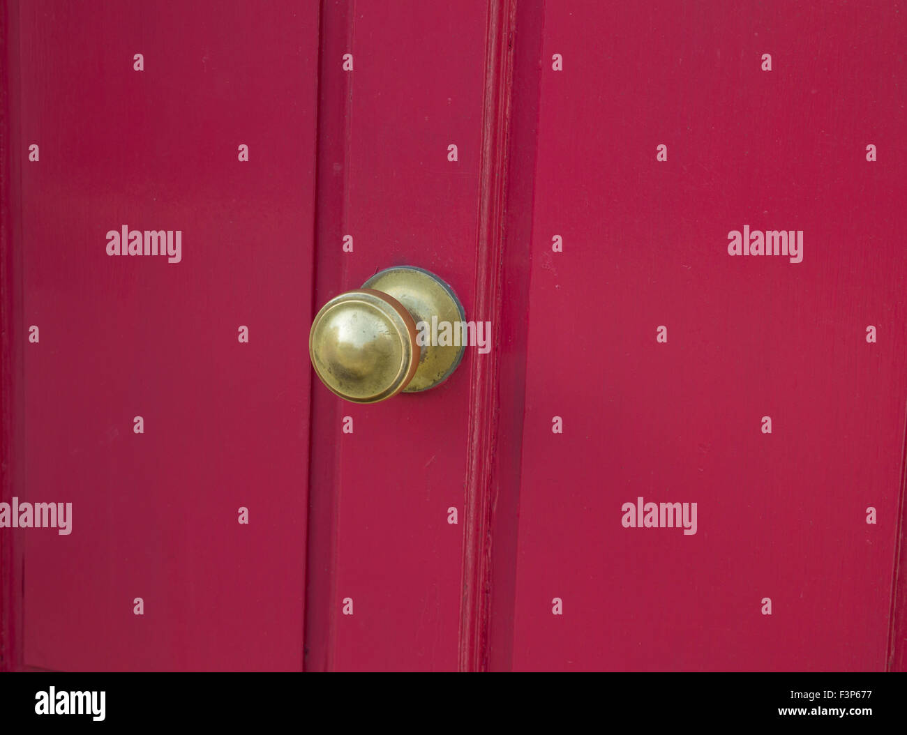 Brass door furniture on a pinky red door Stock Photo