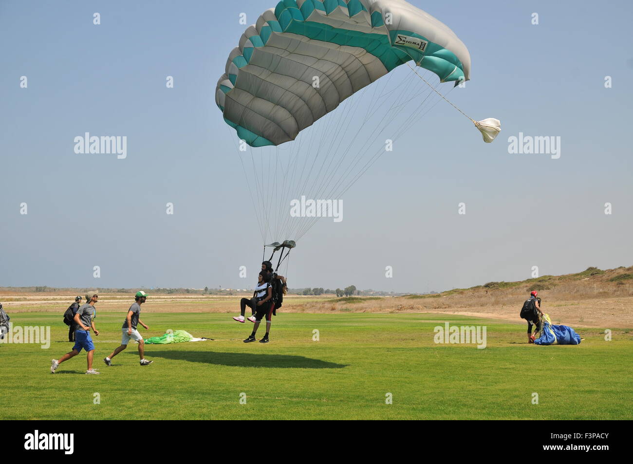 Tandem paragliding Instructor and trainee tied together at landing Stock Photo