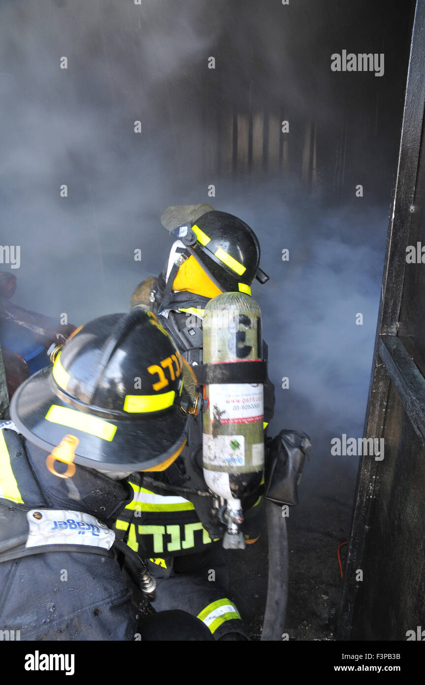 Firefighters with protective equipment in a smoke filled room Stock Photo