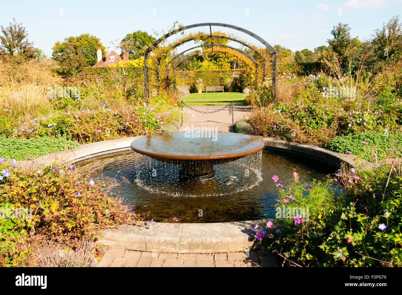 A cottage style garden with a fountain water feature at the Royal Horticultural Society Gardens, Wisley in Surrey. Stock Photo