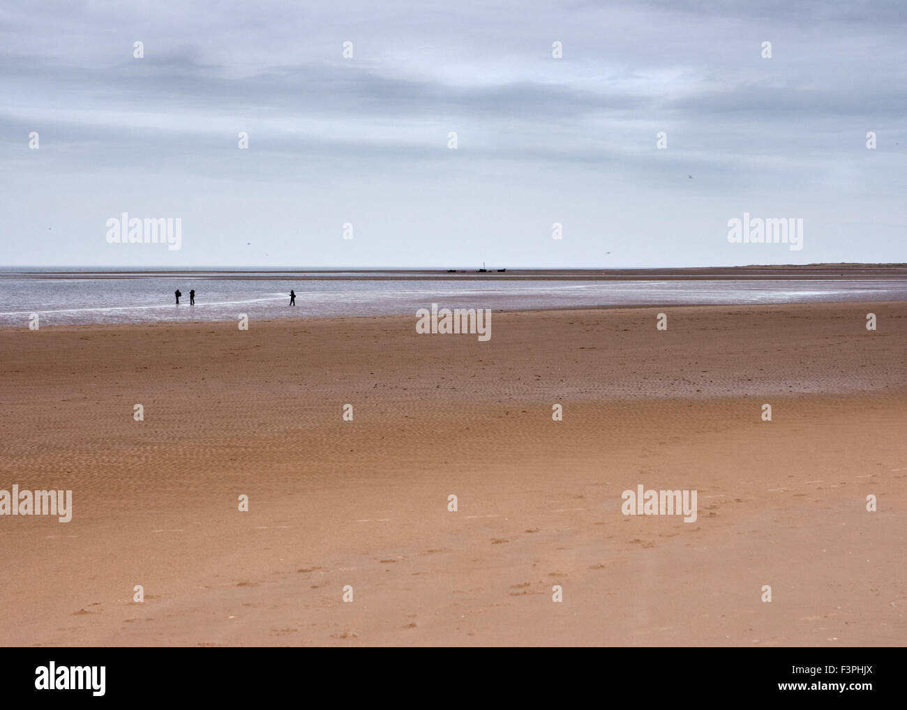 Vast empty beach shoreline and horizon with distant figures Stock Photo