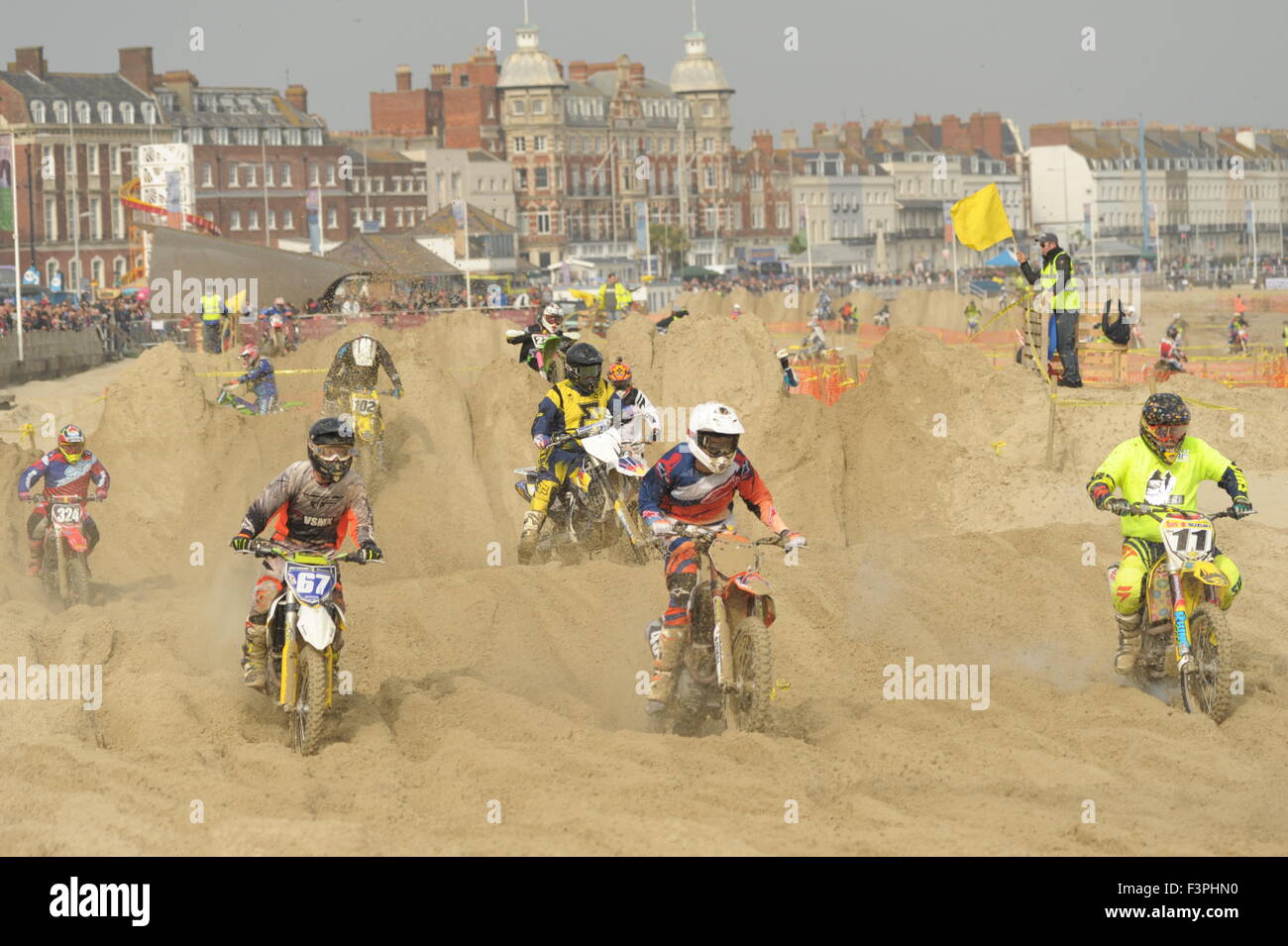 Weymouth, Dorset, UK - 11th October 2015. Annual Lion's Beach motocross weekend on Weymouth Beach.  Weymouth & Portland Lion's  jointly organise the popular event with Purbeck Motocross Club which attracts hundreds of riders, who test themselves on the tricky beach course - Riders competing on the course with the spectacular background of Weymouth seafront - Picture: Graham Hunt/Alamy Live News Stock Photo