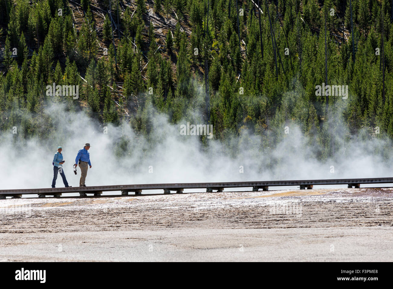 Park visitors walk on the boardwalk along Grand Prismatic Spring, Midway Geyser Basin, Yellowstone National Park, Wyoming, USA Stock Photo