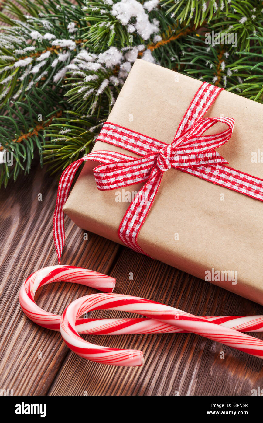 Christmas gift box, candy cane and tree branch on wooden table Stock ...