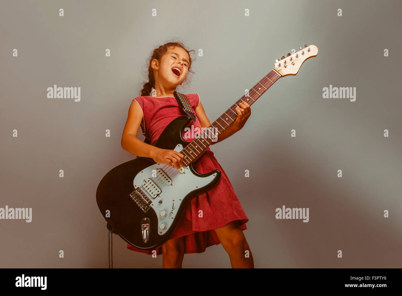 Girl European appearance ten years playing guitar on a blue  bac Stock Photo