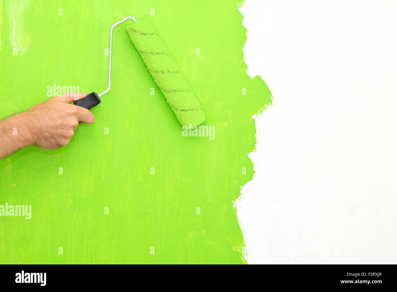 Painting a wall using a roller with green paint Stock Photo - Alamy
