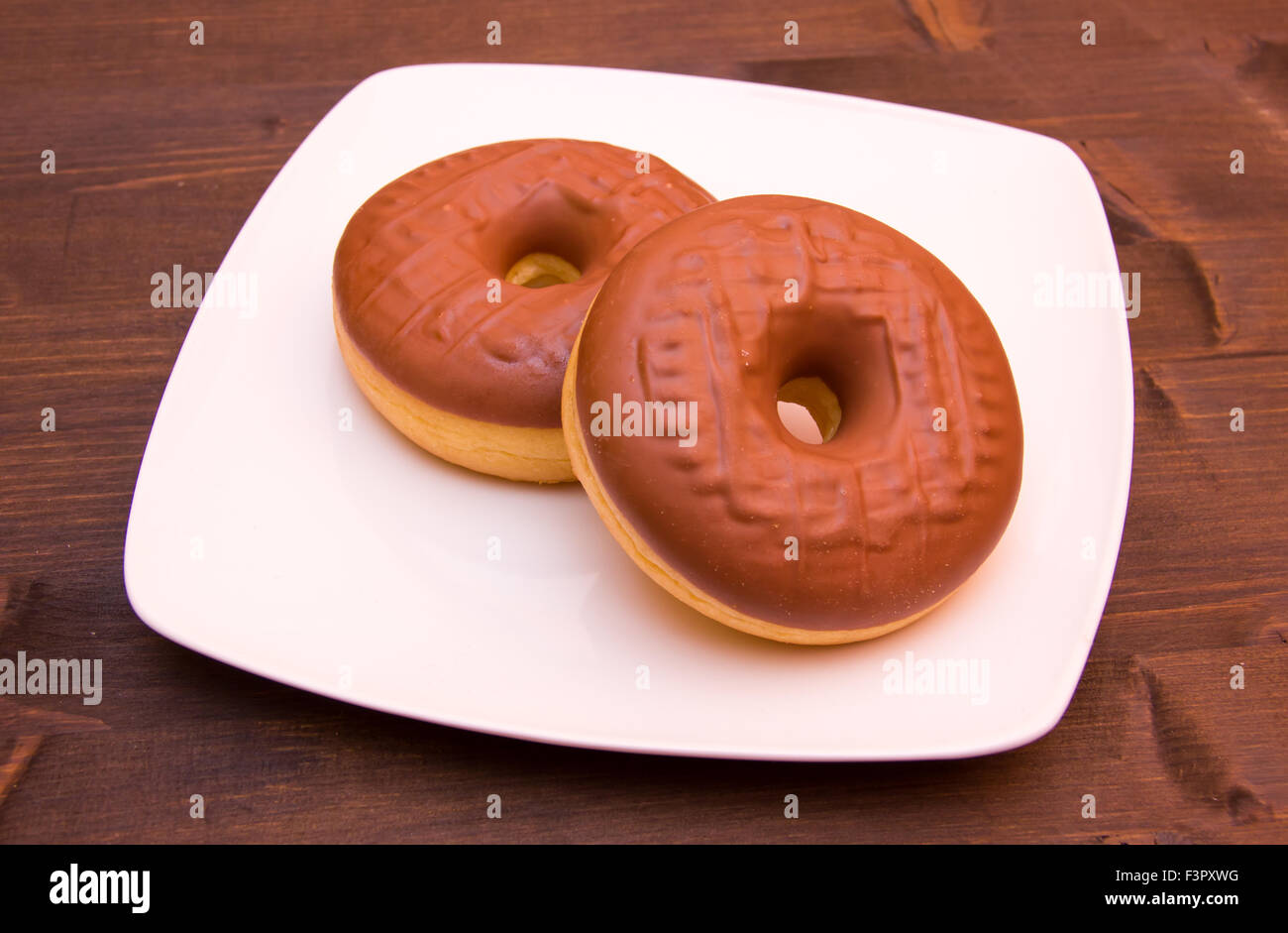 Sweet donuts with chocolate on wooden table Stock Photo - Alamy