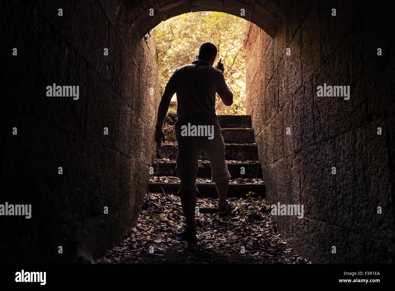 Young man with radio set goes out of dark stone tunnel, warm toned photo, old style filter Stock Photo
