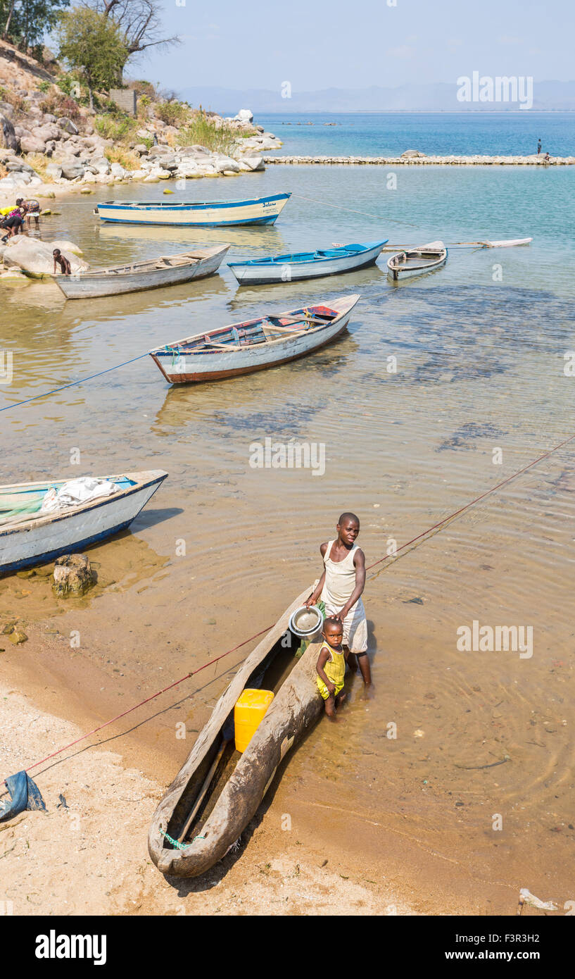 Malawian lifestyle: local people at the lakeside with a dug-out canoe at Ilala Ferry Port, Likoma Island, Lake Malawi, Malawi, south-east Africa Stock Photo