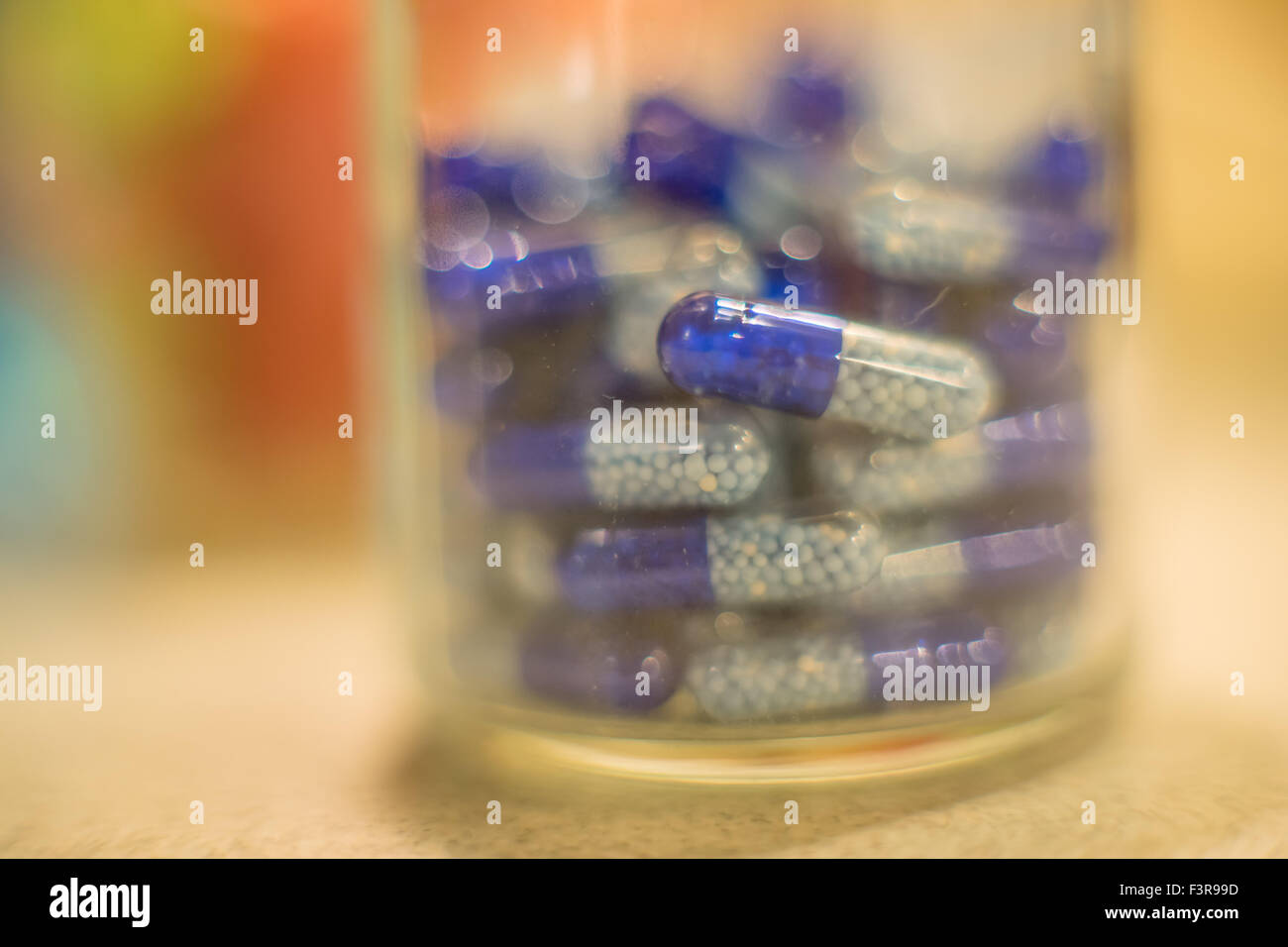 Glass containing white and blue capsules with granules of slow releasing drug Stock Photo