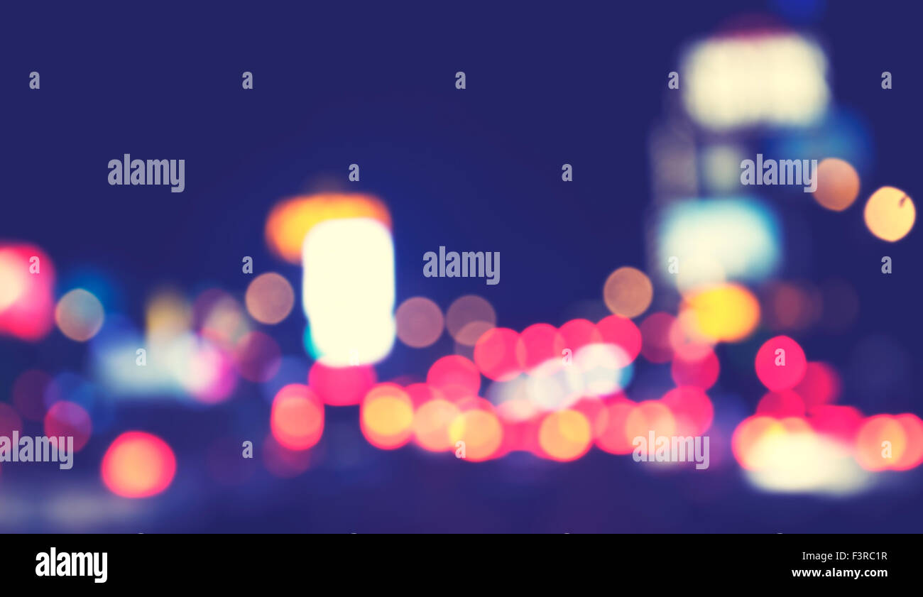 Vintage toned blurred city lights at night, urban abstract background. Stock Photo