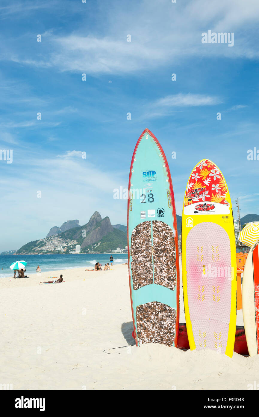 RIO DE JANEIRO, BRAZIL - MARCH 22, 2015: Colorful stand up paddle surfboards stand lined up on the beach at Arpoador. Stock Photo