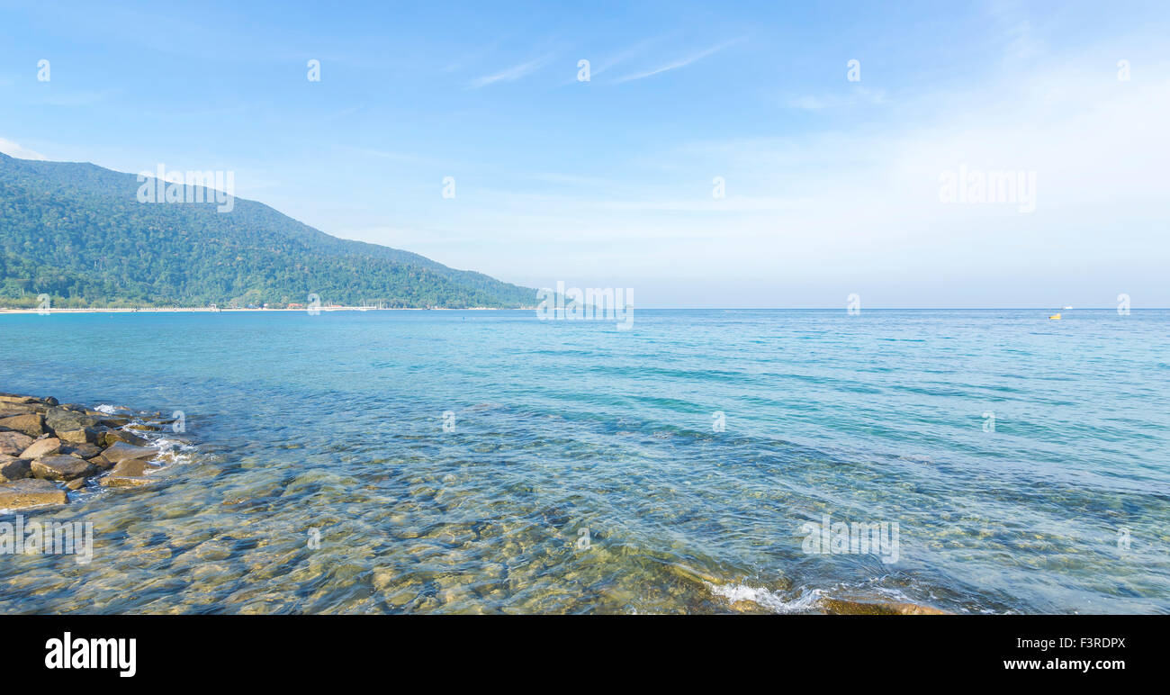 Rock beach with clear water and blue skies Stock Photo - Alamy
