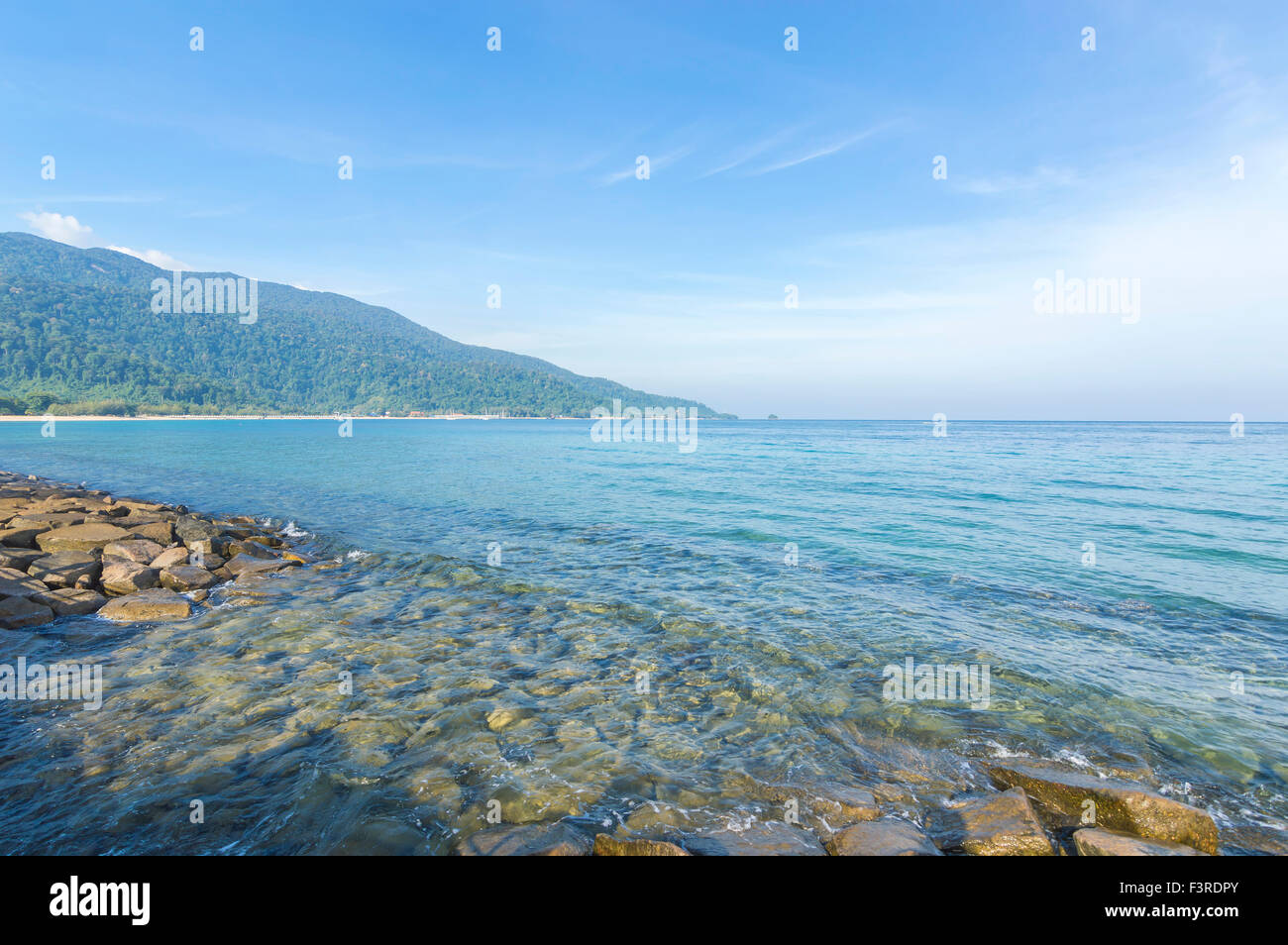 Rock beach with clear water and blue skies Stock Photo - Alamy