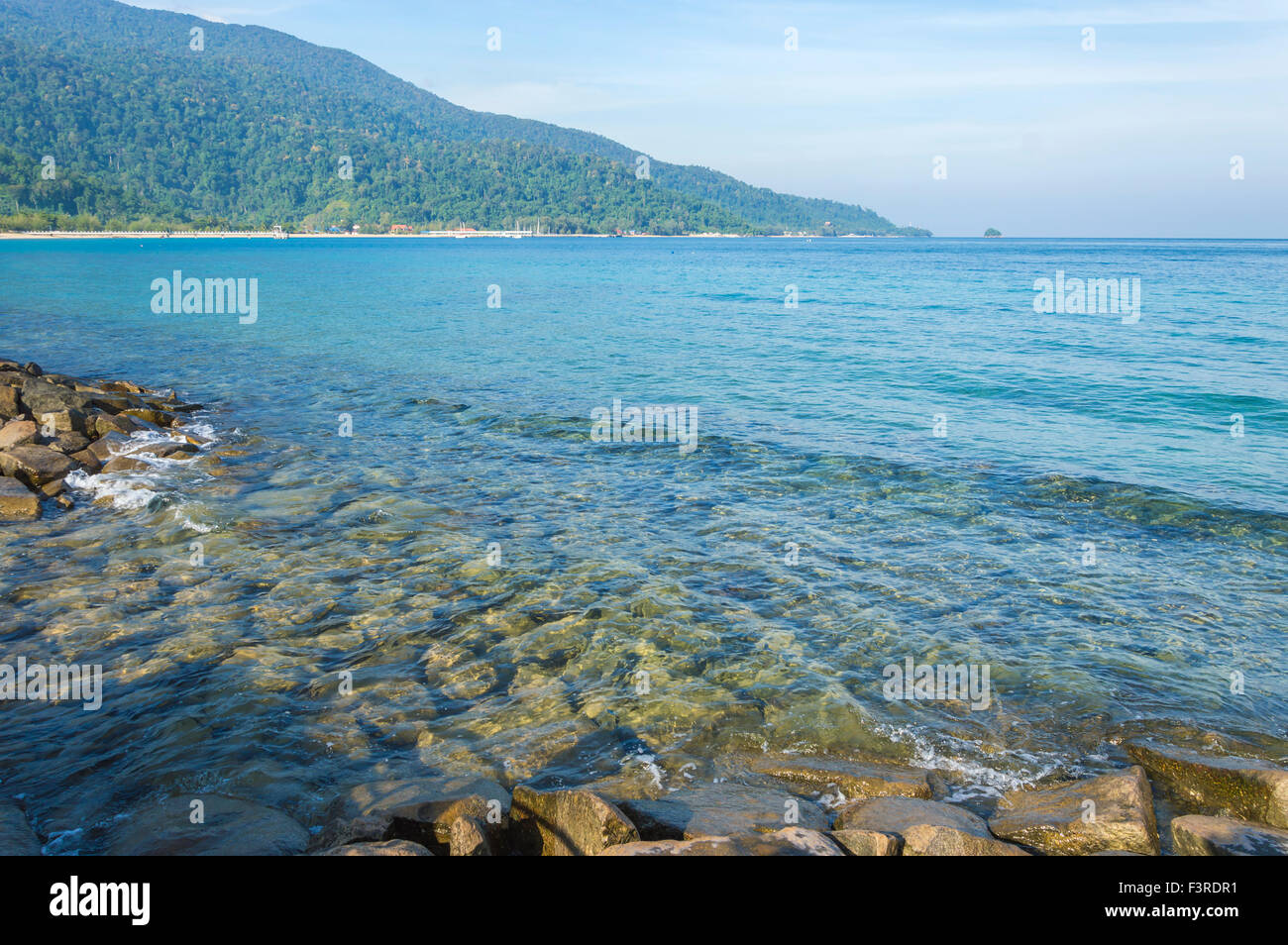Rock beach with clear water and blue skies Stock Photo - Alamy