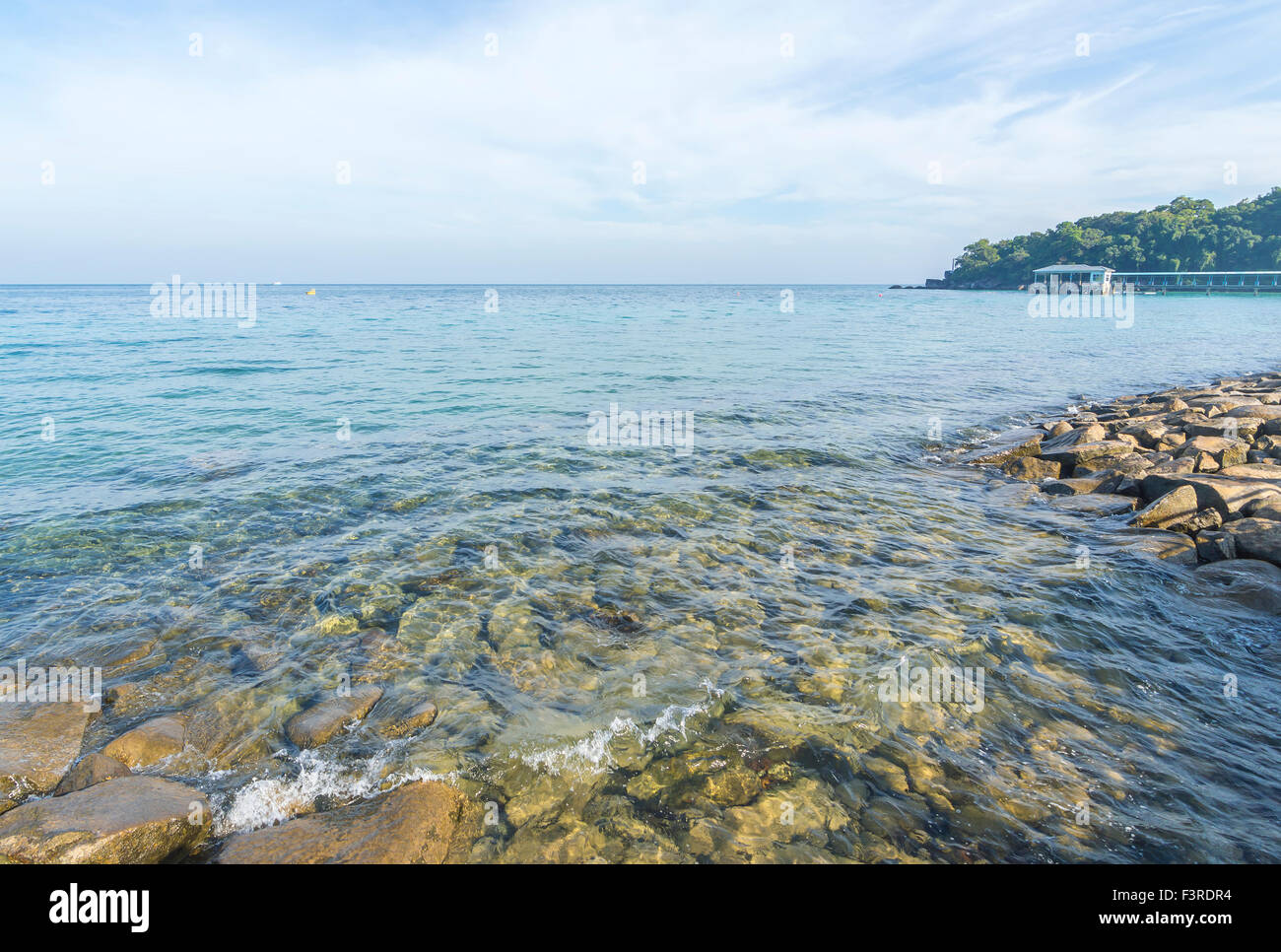 Rock beach with clear water and blue skies Stock Photo - Alamy