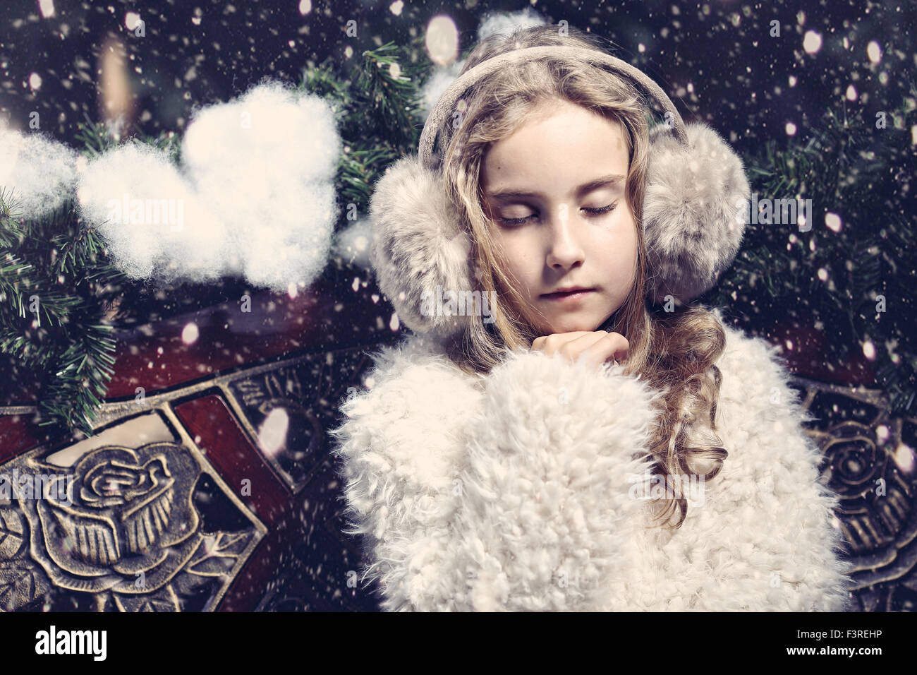 Young girl in earmuffs sitting on a winter day on the bench Stock Photo