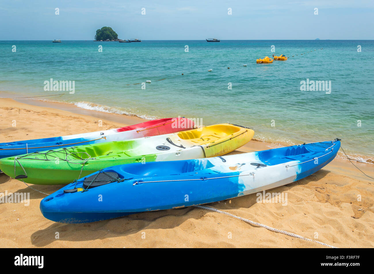 Row of colorful kayaks at sea shore island Stock Photo